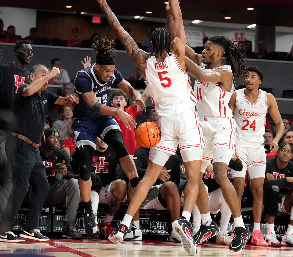New Orleans forward MJ Thomas, left, is pressured by Houston center Chris Cenac Jr. (5) and forward Joseph Tugler (11) during the first half of an NCAA college basketball game, Saturday, Dec. 13, 2025, in Houston. (AP Photo/Karen Warren)