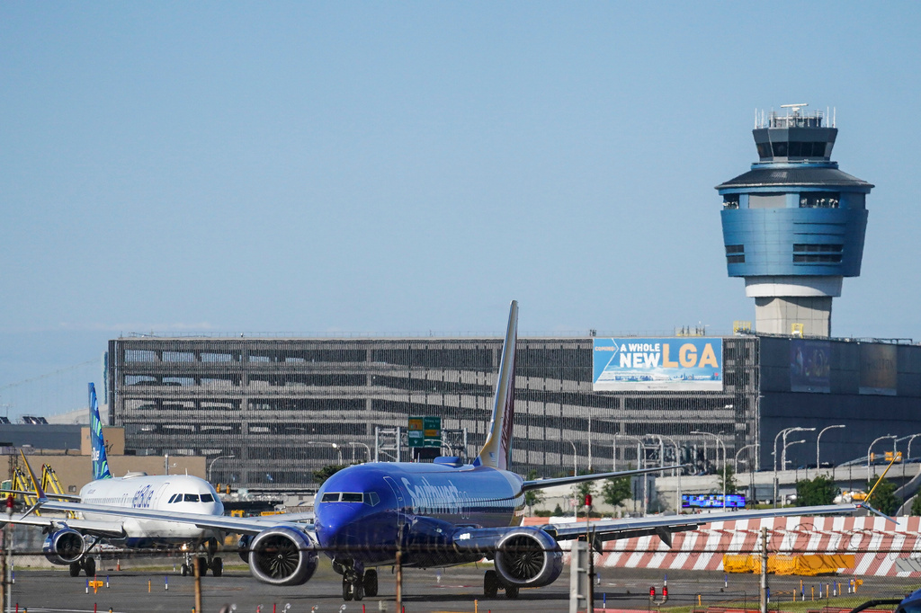 FILE - LaGuardia Airport's air traffic control tower, right, is shown as planes line-up for take-off, Thursday May 25, 2023, in New York. (AP Photo/Bebeto Matthews)