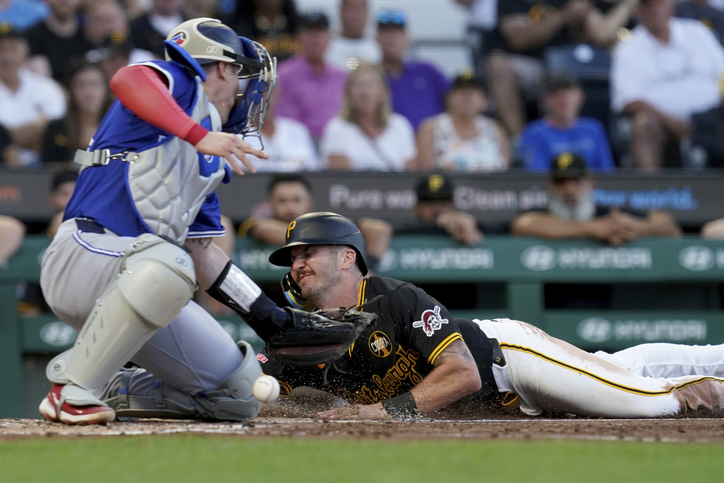 Pittsburgh Pirates' Spencer Horwitz, right, scores as Toronto Blue Jays catcher Tyler Heineman, left, cannot handle a throw during the third inning of a baseball game Monday, Aug. 18, 2025, in Pittsburgh. (AP Photo/Matt Freed)