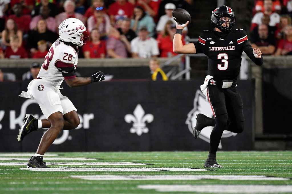 Louisville quarterback Lincoln Kienholz (3) is chased by Florida State linebacker Mikai Gbayor (28) as he attempts a pass during the first half of an NCAA college football game in Louisville, Ky., Friday, Oct. 9, 2026. (AP Photo/Timothy D. Easley)