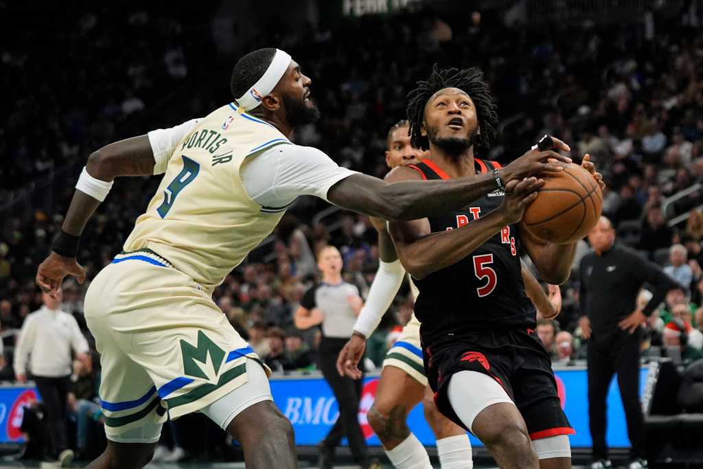 Milwaukee Bucks' Bobby Portis (9) hits the ball away from Toronto Raptors' Immanuel Quickley during the first half of an NBA basketball game, Thursday, Dec. 18, 2025, in Milwaukee. (AP Photo/Aaron Gash)