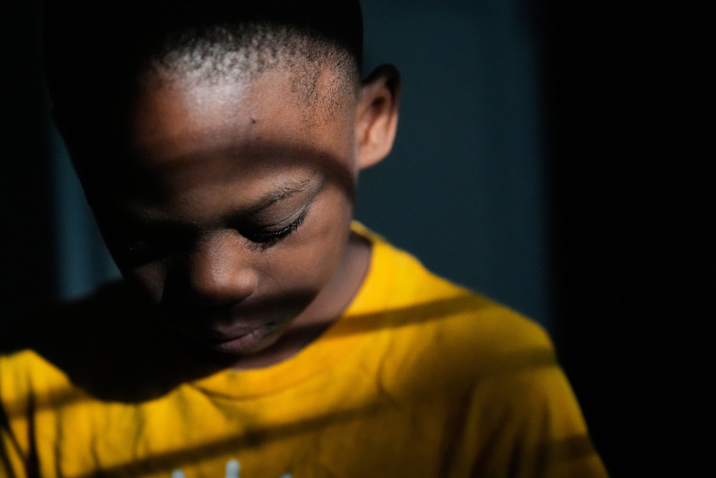 Derrick McNair-White looks down in the kitchen after spilling cereal on the floor, June 7, 2025, in Jonesboro, Ga. McNair-White was adopted by his aunt, Sechita McNair. (AP Photo/Brynn Anderson)