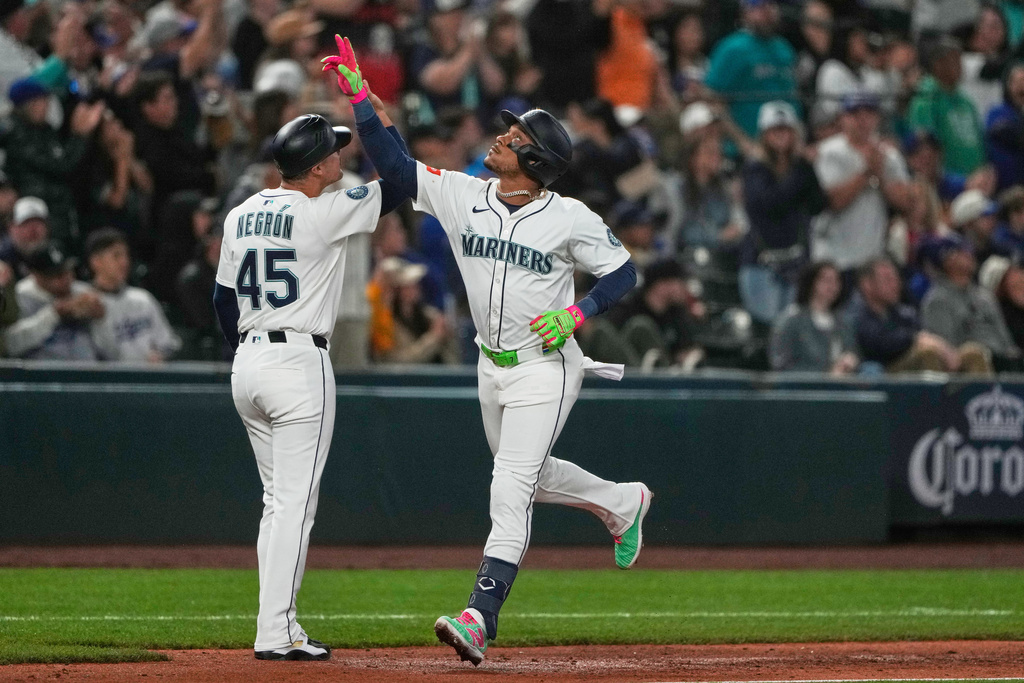 Seattle Mariners' Jorge Polanco, right, celebrates with third base coach Kristopher Negron after hitting a go-ahead three-run home run that also scored Cal Raleigh and Julio Rodriguez during the fifth inning of a baseball game against the Los Angeles Dodgers, Saturday, Sept. 27, 2025, in Seattle. (AP Photo/Ryan Sun)