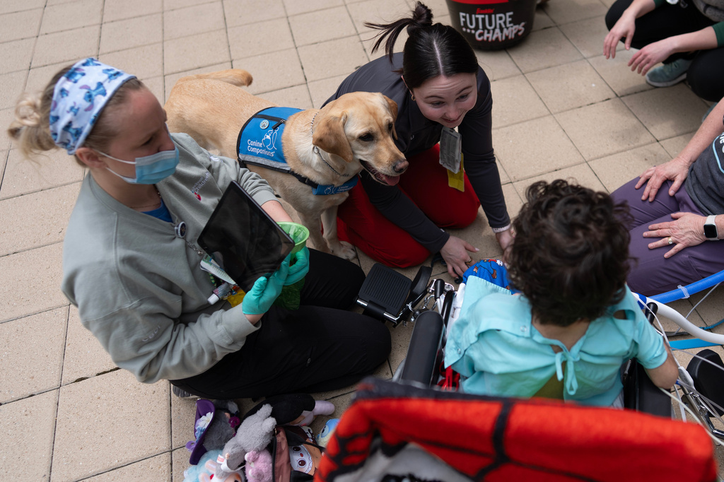 Cincinnati Children's Hospital facility dog Hadley and hospital staff including registered nurse Hanna Hill, right, look to 5-year-old patient Calvin Owens during a physical therapy visit on the patio of Cincinnati Children's Hospital in Cincinnati, Monday, May 4, 2026. (AP Photo/Carolyn Kaster)