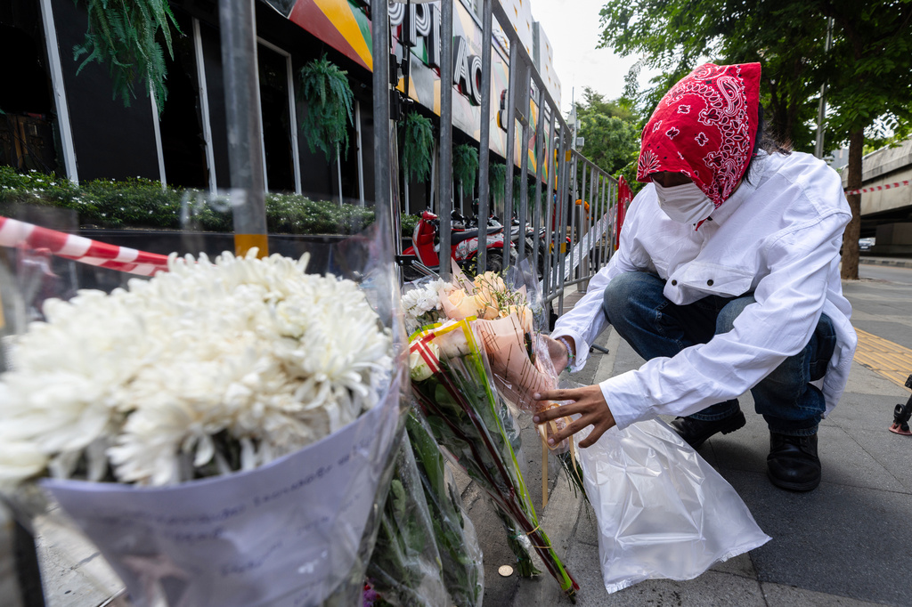 A man puts flowers outside the music bar where a fire killed a number of people in Bangkok, Thailand, Tuesday, July 14, 2026. (AP Photo/Wason Wanichakorn)
