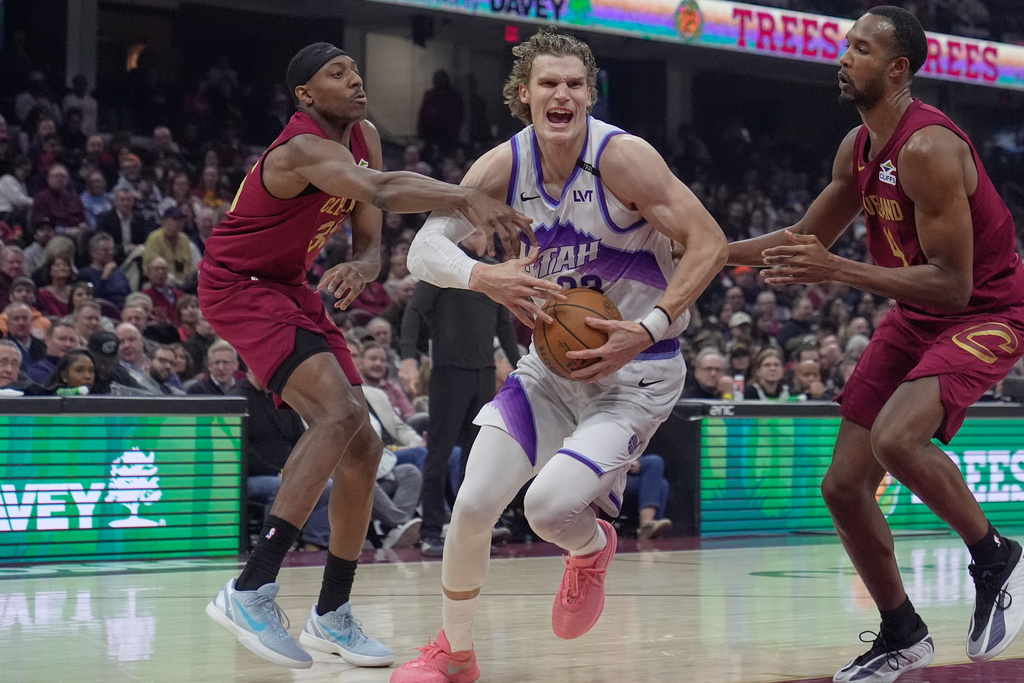 Utah Jazz forward Lauri Markkanen, center, drives between Cleveland Cavaliers forward Nae'qwan Tomlin, left, and center Evan Mobley, right, in the first half of an NBA basketball game in Cleveland, Monday, Jan. 12, 2026. (AP Photo/Sue Ogrocki)