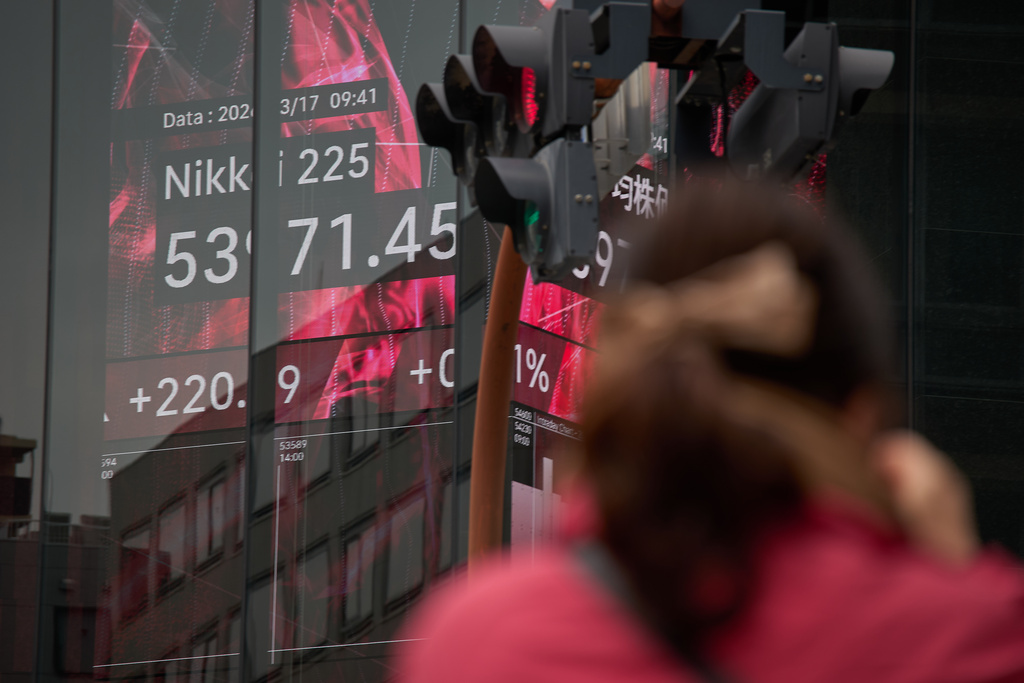 A person stands near a stock price monitor showing Nikkei 225 index at a security company Tuesday, March 17, 2026, in Tokyo. (AP Photo/Eugene Hoshiko)
