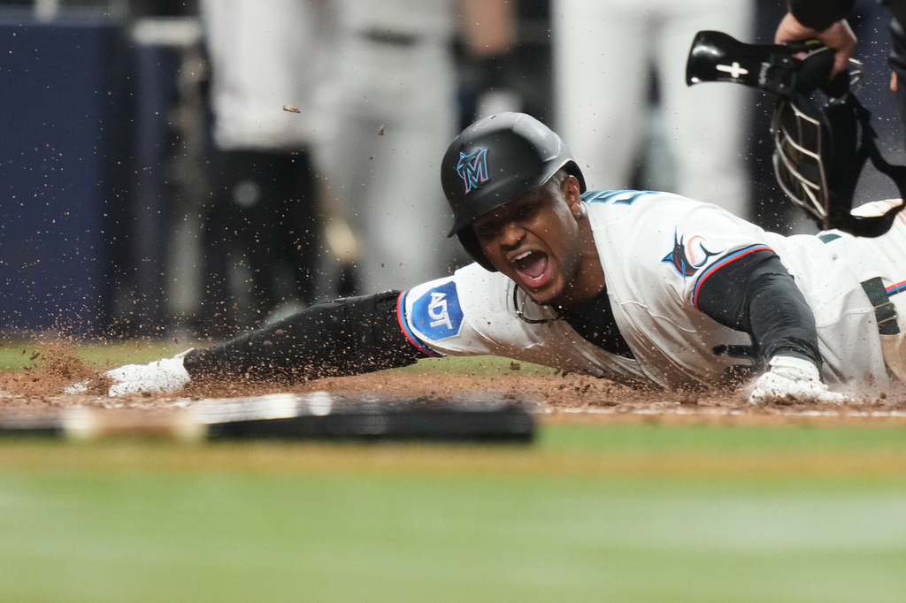 Miami Marlins' Xavier Edwards is out at the plate after hitting a triple to score Otto Lopez during the sixth inning of a baseball game against the Texas Rangers, Monday, June 22, 2026, in Miami. (AP Photo/Lynne Sladky)