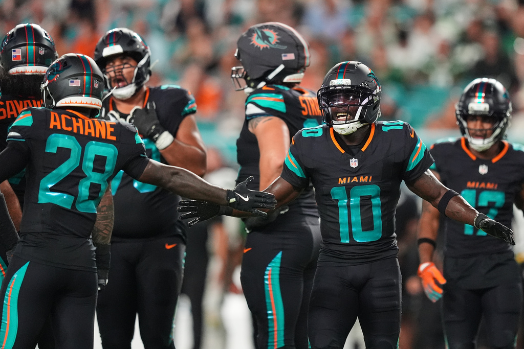 Miami Dolphins' De'Von Achane (28) and Tyreek Hill (10) celebrate after Hill made a catch in the first half of an NFL football game against the New York Jets, Monday, Sept. 29, 2025, in Miami Gardens, Fla. (AP Photo/Rebecca Blackwell)