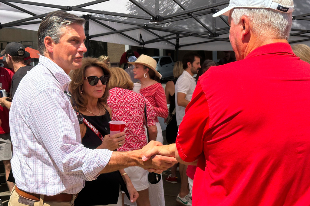 Republican U.S. Senate candidate Derek Dooley, left, speaks to an attendee at a tailgate at the University of Georgia in Athens, Ga., on Saturday, Aug. 30, 2025. (AP Photo/Jeff Amy)