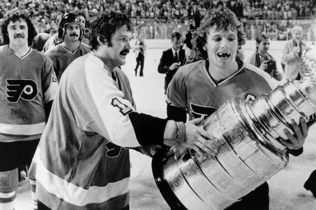 FILE - Philadelphia Flyers' Bernie Parent, left, and Bobby Clarke, carry the Stanley Cup off the ice in Buffalo, May 28, 1975 after defeating the Buffalo Sabres. (AP Photo/File)