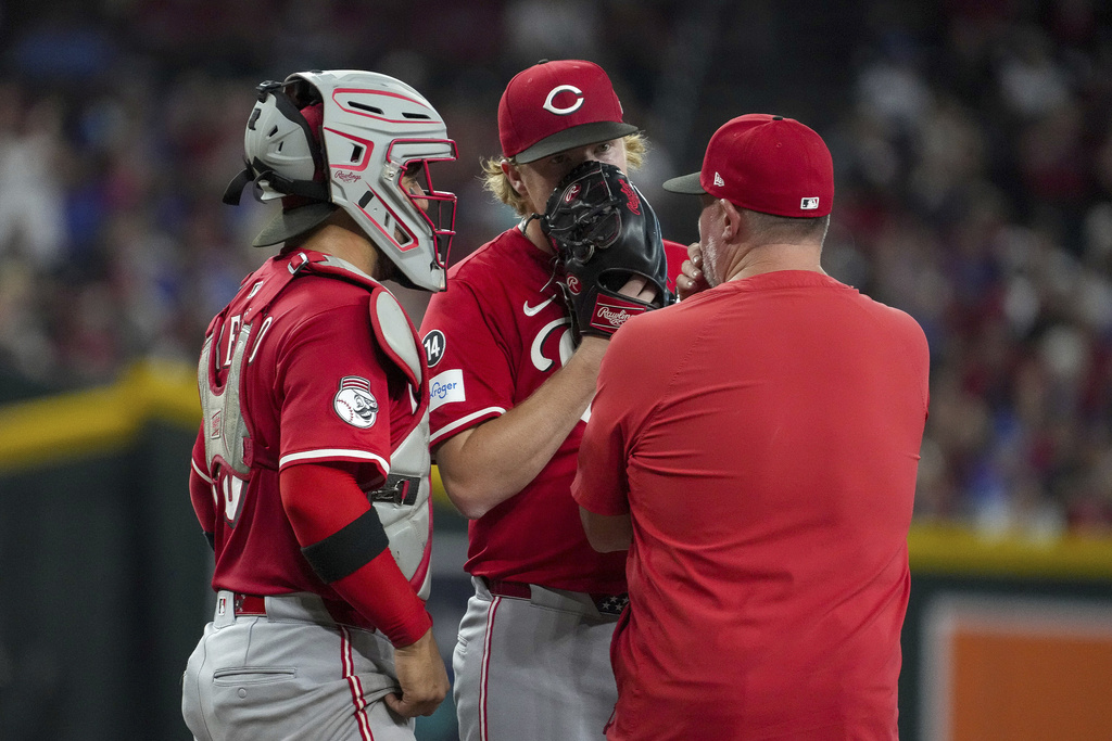 Cincinnati Reds pitcher Andrew Abbott, center, talks with catcher Jose Trevino, left, and pitching Derek Johnson, right, after giving up three runs to the the Arizona Diamondbacks during the first inning of a baseball game Saturday, Aug. 23, 2025, in Phoenix. (AP Photo/Darryl Webb)