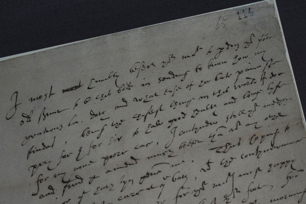 A 16th century letter written by Robert Dudley, 1st Earl of Leicester, to Queen Elizabeth I, on view during a preview of the Love Letters exhibition at the National Archives in London on Wednesday, Jan. 21, 2026, shows two dots written above the word poor, a reference to the monarch's nickname for Dudley: Eyes. (AP Photo/Alastair Grant)