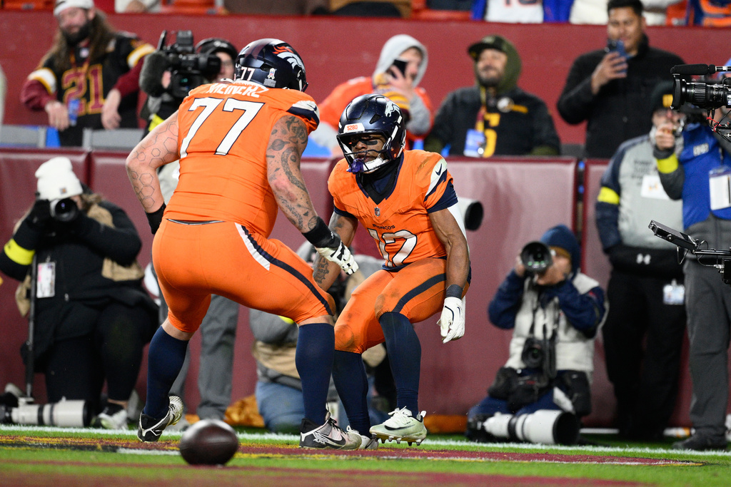 Denver Broncos running back RJ Harvey (12) is congratulated by teammate Quinn Meinerz (77) after scoring during overtime of an NFL football game against the Washington Commanders Sunday, Nov. 30, 2025, in Landover, Md. (AP Photo/Nick Wass)