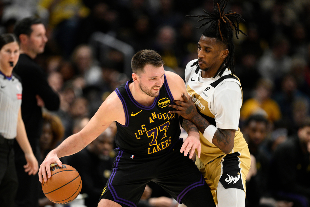 Los Angeles Lakers guard Luka Doncic (77) dribbles against Washington Wizards guard Jamir Watkins, right, during the first half of an NBA basketball game, Friday, Jan. 30, 2026, in Washington. (AP Photo/Nick Wass)