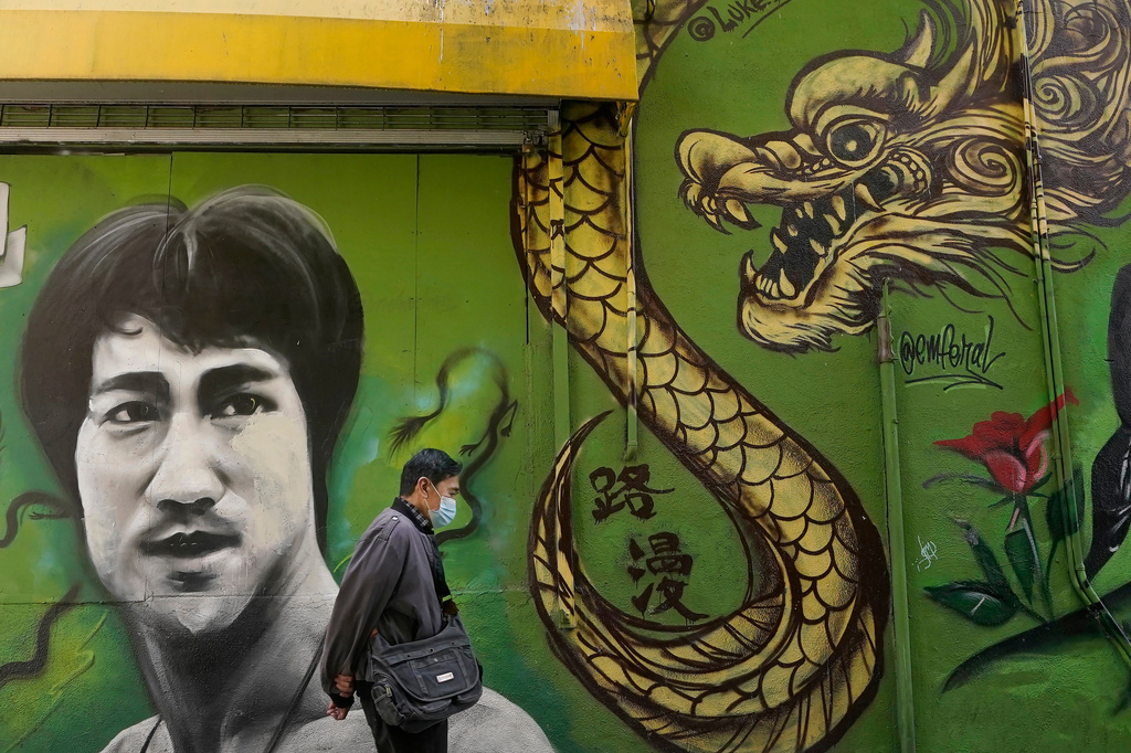 FILE - A man walks past a mural showing Bruce Lee and a dragon in San Francisco, Dec. 30, 2020. (AP Photo/Jeff Chiu, File)