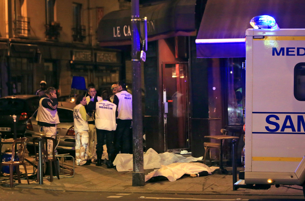 FILE - Medics attend the scene as victims lay on the pavement outside a Paris restaurant, Friday, Nov. 13, 2015. (AP Photo/Thibault Camus, File)