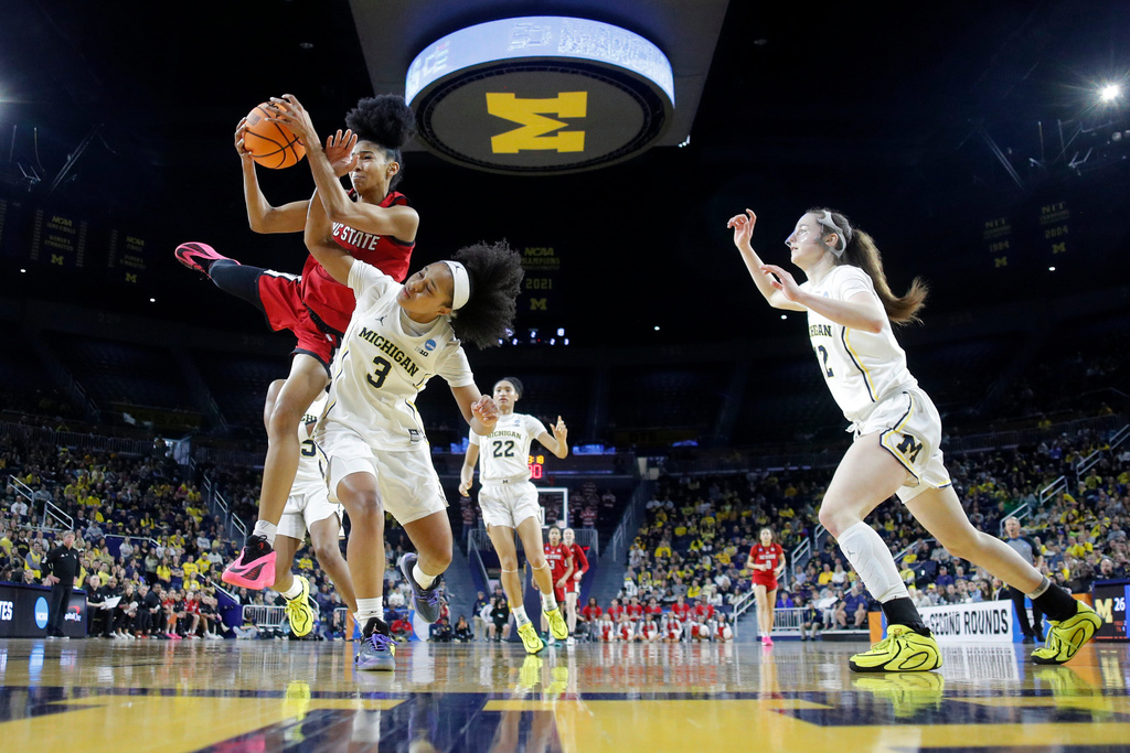 North Carolina State guard Qadence Samuels, top left, and Michigan guard Mila Holloway (3) battle for a rebound as Michigan guard Syla Swords, right, moves in during the first half in the second round of the NCAA college basketball tournament, Sunday, March 22, 2026, in Ann Arbor, Mich. (AP Photo/Al Goldis)