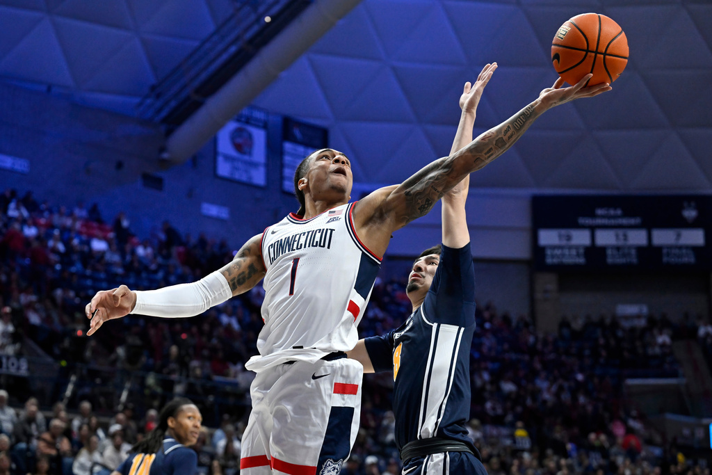 UConn guard Solo Ball (1) makes a basket as East Texas A&M's Damian Garcia defends in the first half of an NCAA college basketball game, Friday, Dec. 5, 2025, in Storrs, Conn. (AP Photo/Jessica Hill)