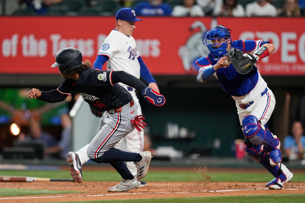 Minnesota Twins' Austin Martin is chased and thrown out at third by Texas Rangers catcher Kyle Higashioka, right, as Martin tried to advance home on a fielders choice by Luke Keaschall in the third inning of a baseball game Tuesday, Sept. 23, 2025, in Arlington, Texas. (AP Photo/Tony Gutierrez)