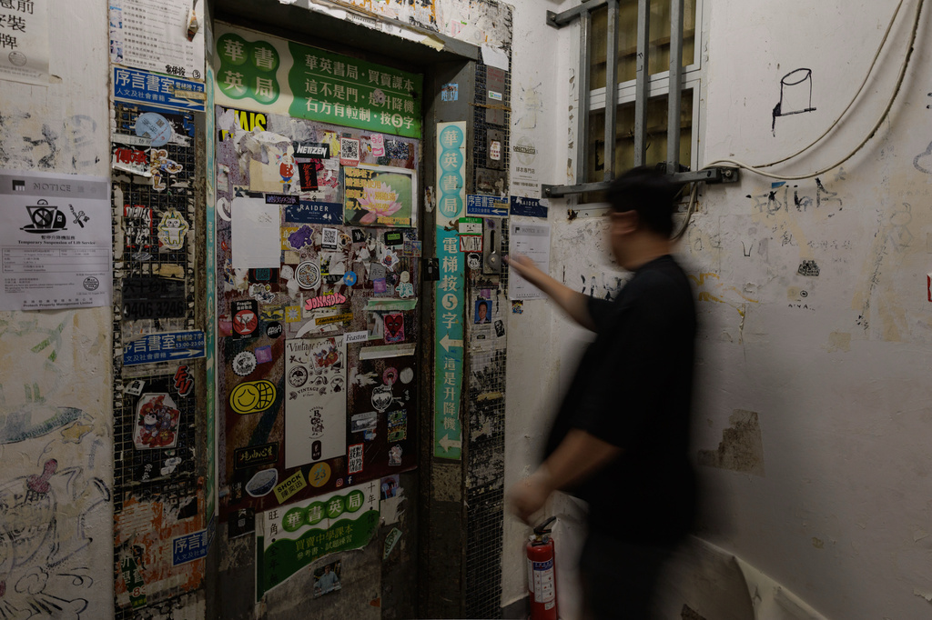 A person waits for the lift leading to various shops including Hong Kong Reader Bookstore in Hong Kong, Friday, Aug. 14, 2026. (AP Photo/May James)