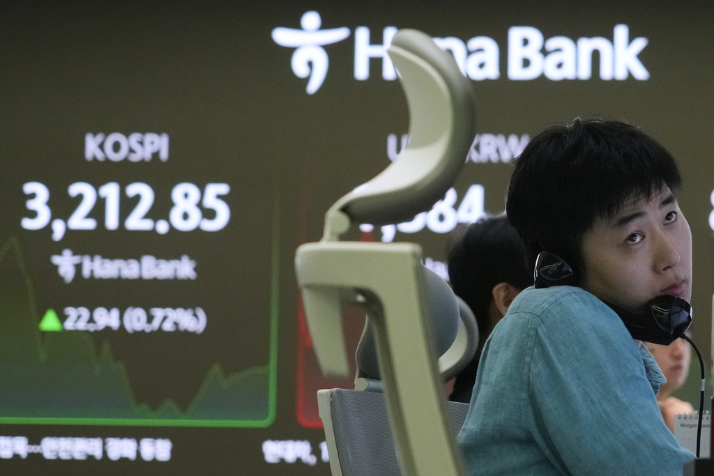 A currency trader talks on the phone near a screen showing the Korea Composite Stock Price Index (KOSPI) at the foreign exchange dealing room of the Hana Bank headquarters in Seoul, South Korea, Wednesday, Aug. 13, 2025. (AP Photo/Ahn Young-joon)