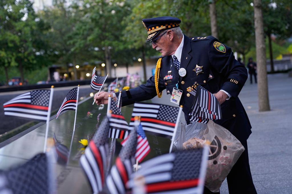 Sam Pulia places flags on names inscribed in the 9/11 Memorial before the start of a ceremony commemorating the 24th anniversary of the Sept. 11, 2001, attacks, Thursday, Sept. 11, 2025, in New York. (AP Photo/Seth Wenig)