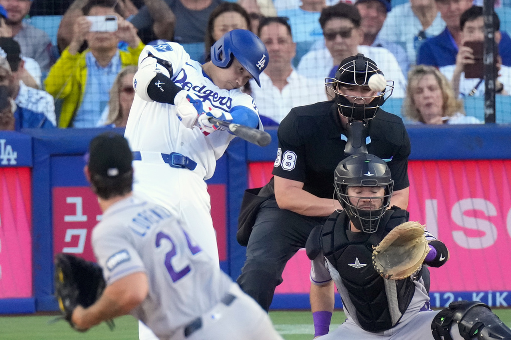 Los Angeles Dodgers' Shohei Ohtani, second from left, hits a solo home run as Colorado Rockies starting pitcher Michael Lorenzen, left, and Braxton Fulford watch during the first inning of a baseball game Tuesday, July 7, 2026, in Los Angeles. (AP Photo/Mark J. Terrill)