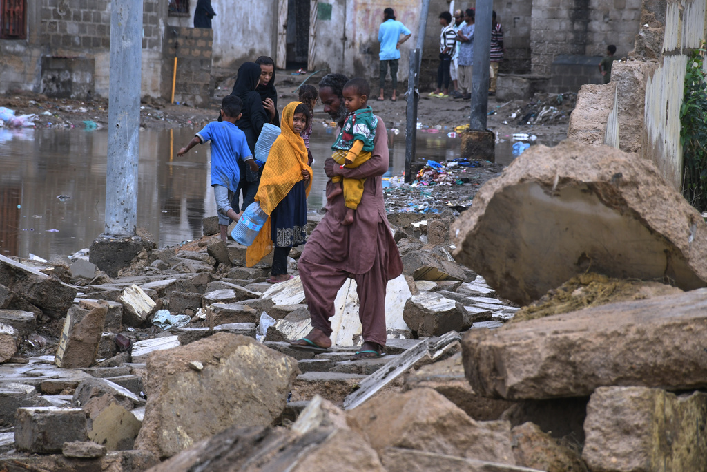 Local residents navigate through the rubble of boundary wall collapsed due to heavy rains and strong winds in Karachi, Pakistan, Thursday, March 19, 2026. (AP Photo/Ali Raza)