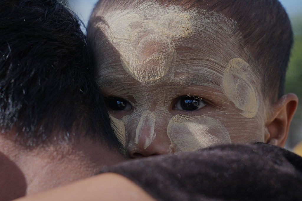 A father carrying his child lines up to cast vote at a polling station in Naypyitaw, Myanmar, Sunday, Dec. 28, 2025. (AP Photo/Aung Shine Oo)