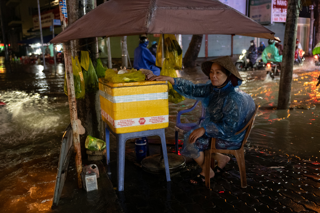 A woman sells food surrounded by floodwaters rain and high tide cause flooding on Pham Huu Lau Street in Ho Chi Minh City, Vietnam, Wednesday, Sept. 30, 2026. (AP Photo/Thanh Hue)