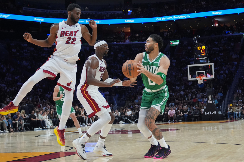 Miami Heat forward Andrew Wiggins (22) and center Bam Adebayo, center, defend Boston Celtics forward Jayson Tatum (0) during the first half of an NBA basketball game, Wednesday, April 1, 2026, in Miami. (AP Photo/Lynne Sladky)