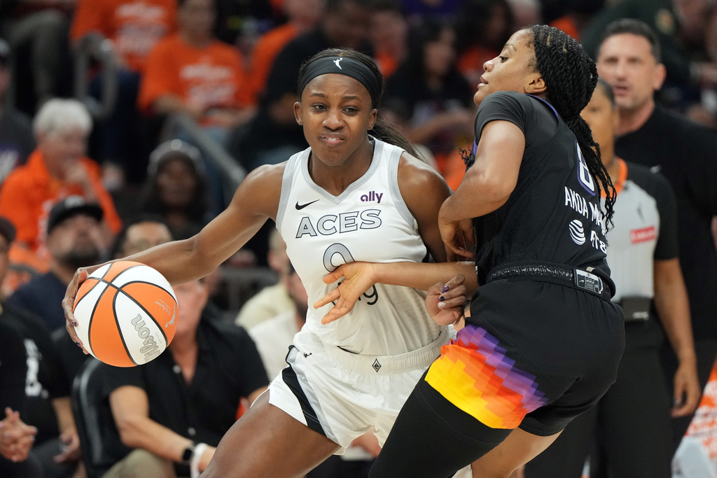 Las Vegas Aces guard Jackie Young drives on Phoenix Mercury guard Monique Akoa Makani (8) during the first half of Game 3 of the WNBA basketball finals, Wednesday, Oct. 8, 2025, in Phoenix. (AP Photo/Rick Scuteri)