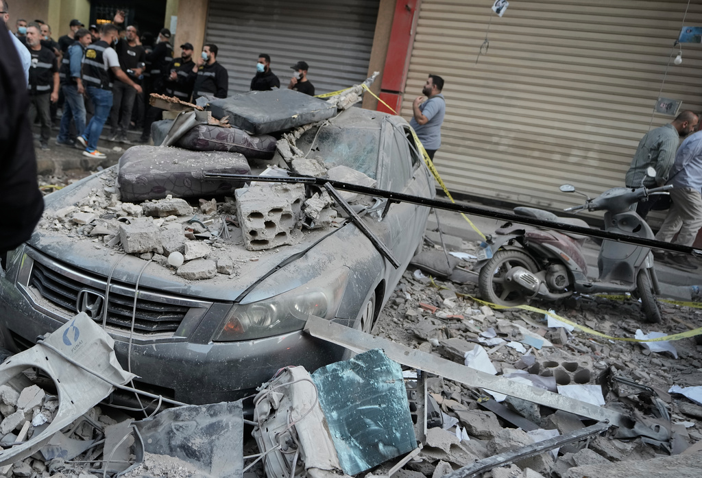 Security officers gather near destroyed vehicles at the site where an Israeli strike hit at an apartment building in Dahiyeh, a southern suburb of Beirut, Sunday, Nov. 23, 2025. (AP Photo/Bilal Hussein)