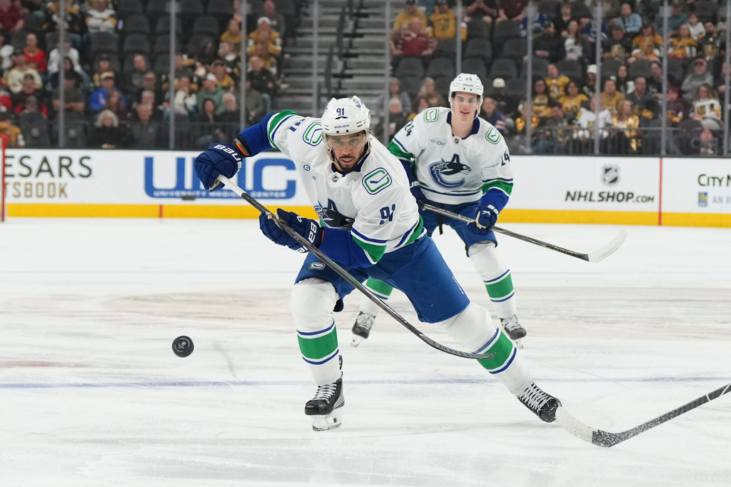 Vancouver Canucks left wing Evander Kane (91) chases after the puck against the Vegas Golden Knights during the first period of an NHL hockey game Monday, March 30, 2026, in Las Vegas. (AP Photo/Candice Ward)