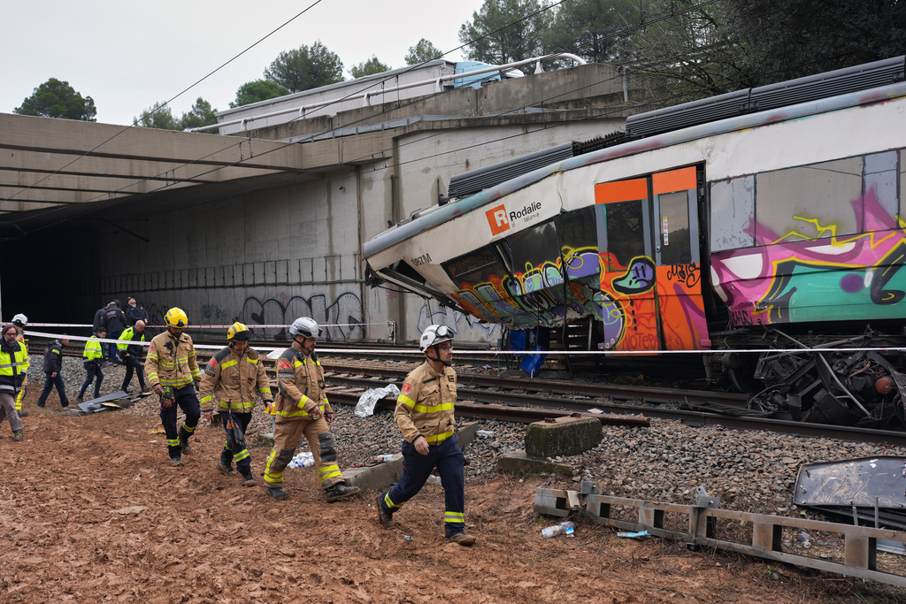 Police officers and firefighters inspect the damage after a commuter train derailed as a retaining wall collapsed onto the tracks in Gelida, near Barcelona, Spain, Wednesday, Jan. 21, 2026. (AP Photo/Joan Mateu Parra)
