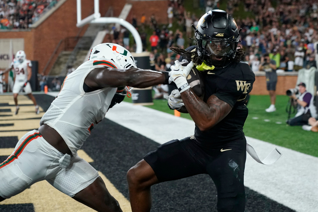 Wake Forest tight end Kamrean Johnson, right, catches a touchdown pass as Miami linebacker Mohamed Toure, left, defends during the first half of an NCAA college football game in Winston-Salem, N.C., Friday, Sept. 18, 2026. (AP Photo/Chuck Burton)