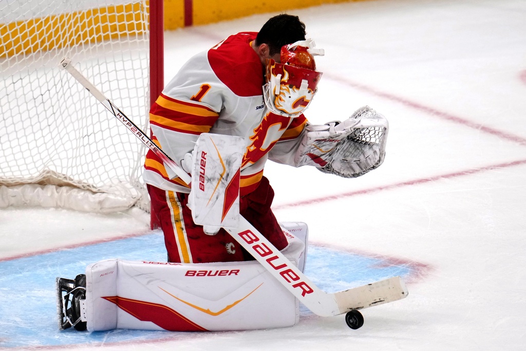 Calgary Flames goaltender Devin Cooley has his mask knocked off by a shot on goal during the first period of an NHL hockey game against the Pittsburgh Penguins in Pittsburgh, Saturday, Jan. 10, 2026. (AP Photo/Gene J. Puskar)