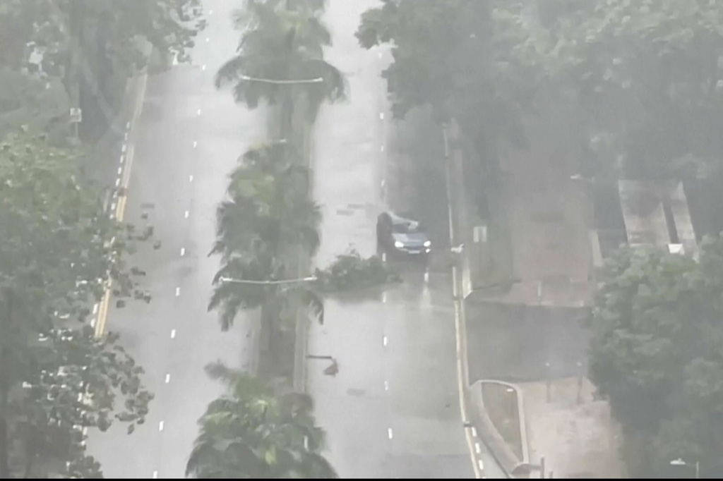 In this image taken from video footage, a car navigates past fallen tree branches as the tropical storm Tapah hits Hong Kong early Monday Sept. 8, 2025. (AP Photo)