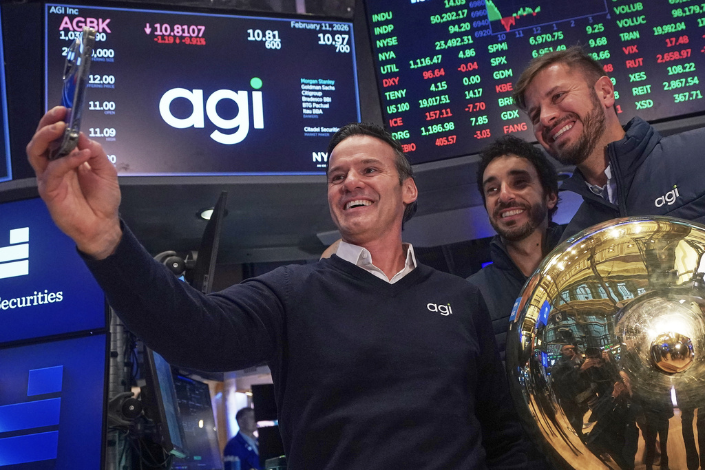 AGI Inc Founder, Executive Chairman & CEO Marciano Testa, left, Governance Officer Lucas Aguiar, center, and Chief Client Officer Matheus Girardi take a selfie photo on the floor of the New York Stock Exchange after their company's IPO began trading, Wednesday, Feb. 11, 2026. (AP Photo/Richard Drew)