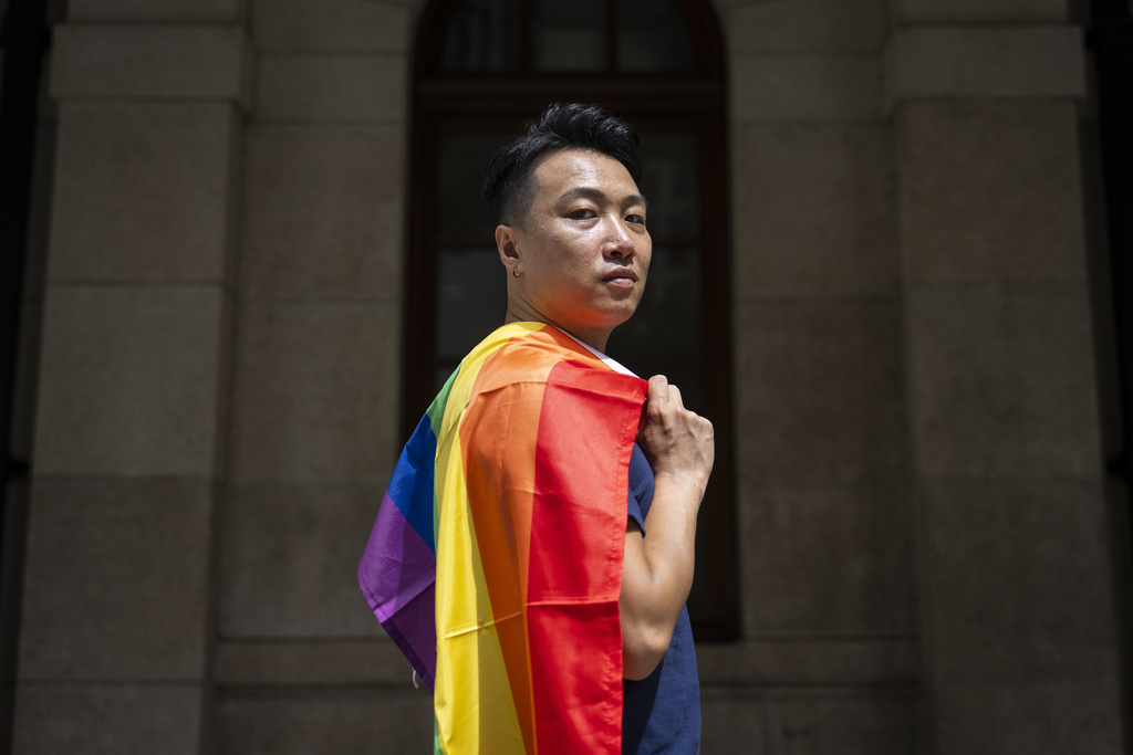 Jimmy Sham, gay rights activist and former pro-democracy district councillor, holds rainbow flag as he poses for photographs in front of the court of final appeal in Hong Kong, Sunday, Aug. 24, 2025. (AP Photo/Chan Long Hei)