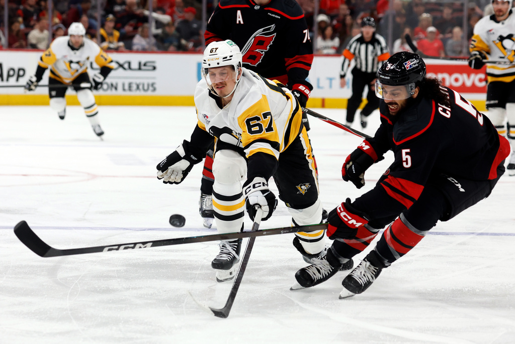 Pittsburgh Penguins' Rickard Rakell (67) chips the puck past Carolina Hurricanes' Jalen Chatfield (5) during the first period of an NHL hockey game in Raleigh, N.C., Tuesday, March 10, 2026. (AP Photo/Karl DeBlaker)
