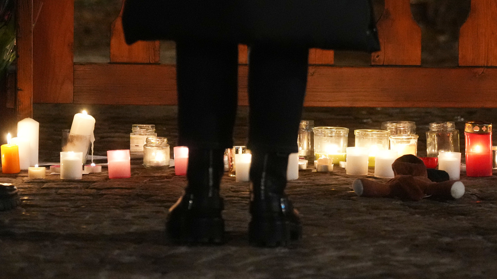People lay candles and flowers near the Le Constellation bar, where a devastating fire left dead and injured during the New Year's celebrations in Crans-Montana, Swiss Alps, Switzerland, Thursday, Jan. 1, 2026. (AP Photo/ Antonio Calanni)