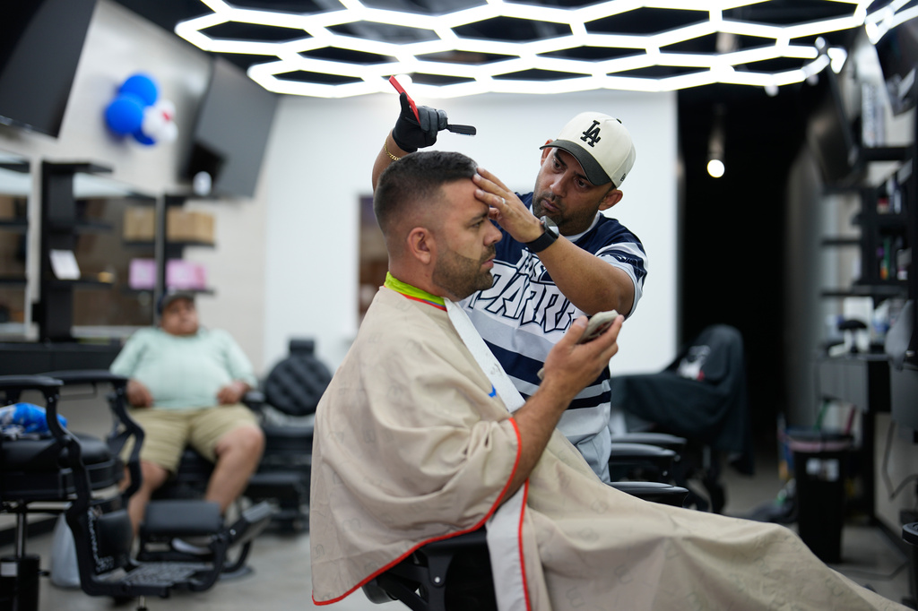 Barber Diego Contreras cuts the hair of fellow Venezuelan Diego Parra on Wednesday, July 15, 2026, in Midvale, Utah. (AP Photo/Gregory Bull)