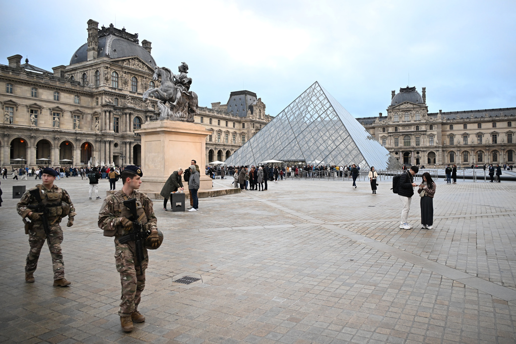 Soldiers patrol as people queue to try to enter the Louvre museum, although it remains closed for the day after Sunday's jewels robbery, Monday, Oct. 20, 2025 in Paris. (AP Photo/Emma Da Silva)