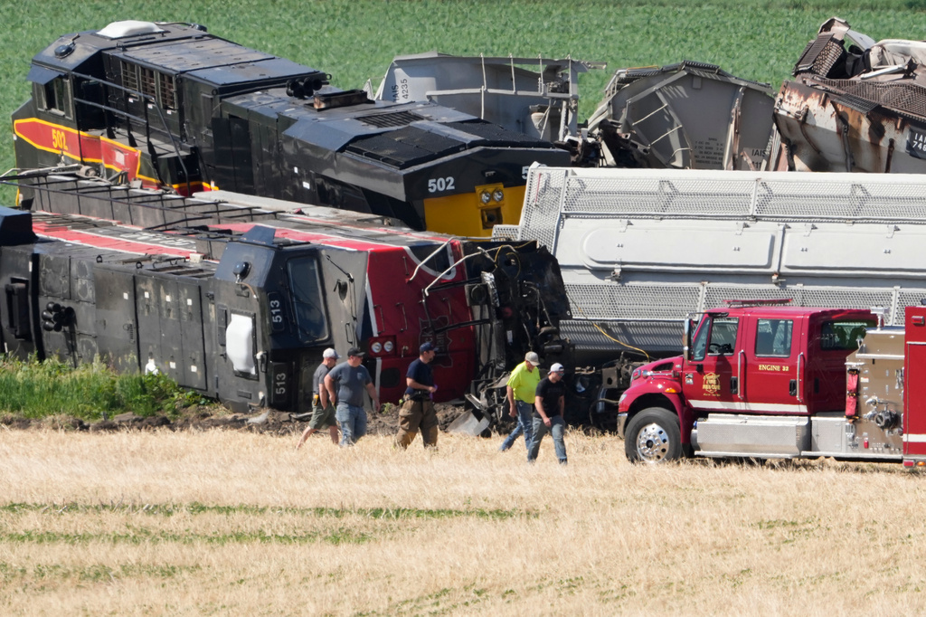 Workers and first responders walk past damage after a train derailed on Wednesday, June 3, 2026, near Victor, Iowa. (AP Photo/Charlie Neibergall)