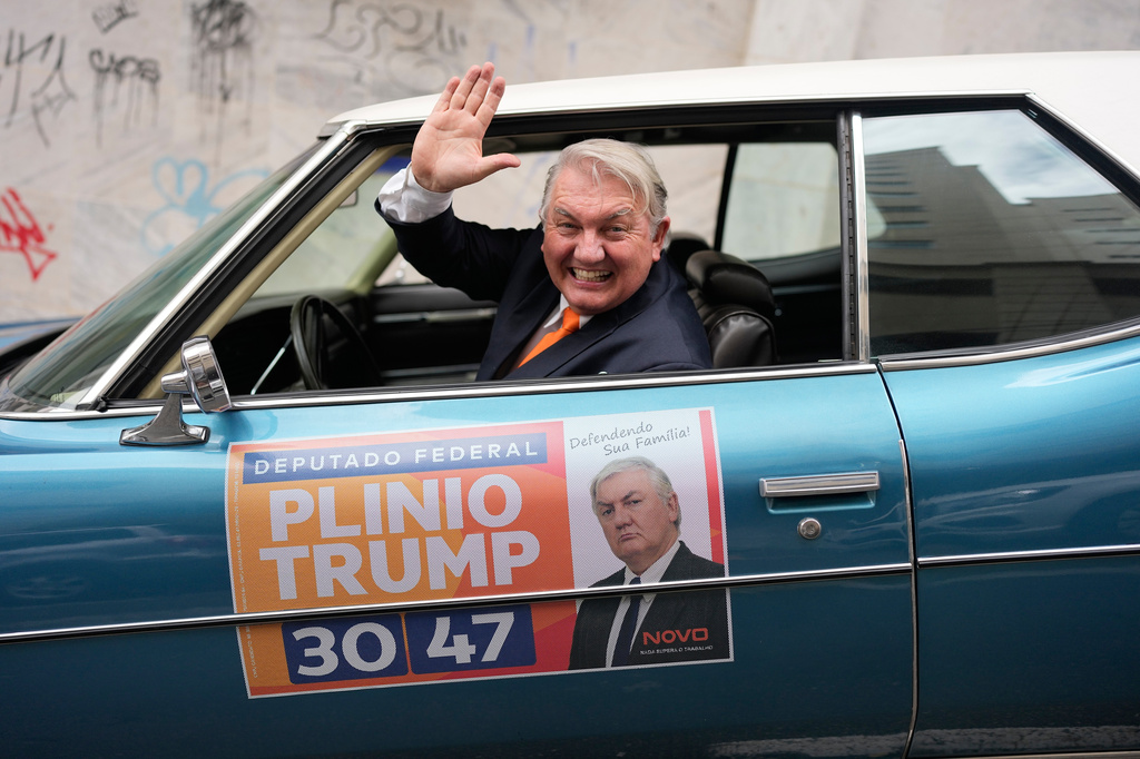 Plinio Vicentin Jr., who is running for federal lawmaker as "Plinio Trump," with the Novo Party representing Minas Gerais state, campaigns from his car ahead of the general election in Juiz de Fora, Minas Gerais state, Brazil, Monday, Sept. 28, 2026. (AP Photo/Silvia Izquierdo)