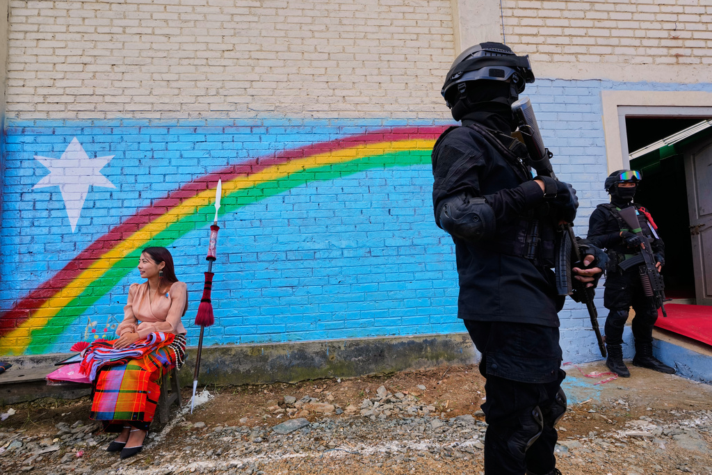 A woman sits in front of a graffiti of the Naga flag, near cadres of the National Socialist Council of Nagaland (Isak-Muivah) cadres in Ukhrul, in the northeastern Indian state of Manipur, Wednesday, Oct. 22, 2025. (AP Photo/Anupam Nath)