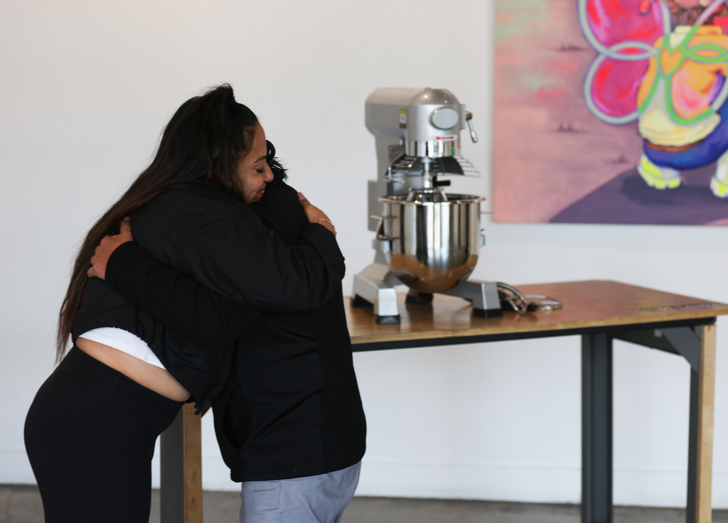 Community organizer Delilah Martinez hugs a baker in the historically Mexican-American Chicago after revealing local community members gifted a mixer to him during an interview at Vault Gallerie, Wednesday, Oct. 29, 2025. (AP Photo/Talia Sprague)