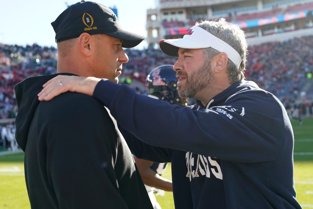 Tulane football coach Jon Sumrall, left, and Mississippi football coach Pete Golding greet each other prior to the first half of the first round of the NCAA College Football Playoff, Saturday, Dec. 20, 2025, in Oxford, Miss. (AP Photo/Rogelio V. Solis)